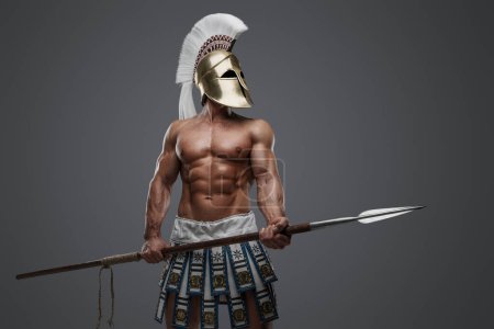Photo for Studio shot of strong greek man with plumed helmet and spear against gray background. - Royalty Free Image