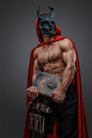 Foto de Tiro de brujo musculoso hombre de hermandad oscura vestido con manto rojo y máscara malvada. - Imagen libre de derechos