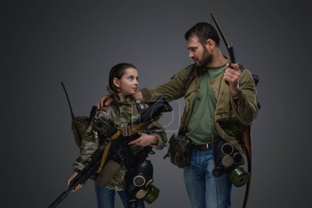 Téléchargez les photos : Portrait of man with young girl with rifle and handgun surviving after disaster. - en image libre de droit