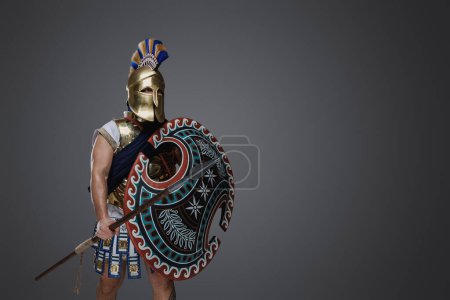 Téléchargez les photos : Tourné d'isolé sur fond gris ancien seigneur de guerre de la Grèce avec lance. - en image libre de droit