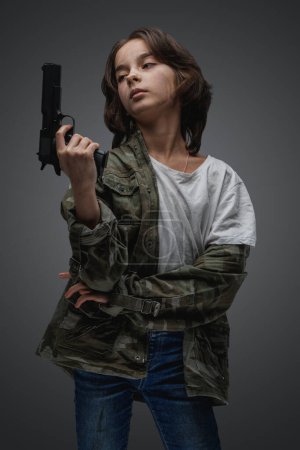 Foto de Shot de post apocalíptica valiente joven vestida con camuflaje chaqueta sosteniendo pistola. - Imagen libre de derechos