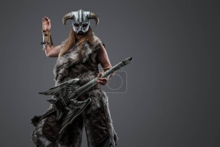 Photo for Studio shot of fierce warrior from north with fur playing electric guitar. - Royalty Free Image