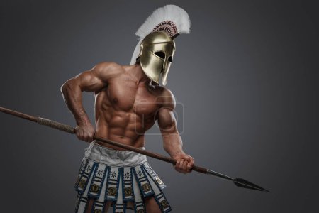 Téléchargez les photos : Prise de vue d'un athlète grec au corps et à la lance parfaits habillés d'un casque à plumes. - en image libre de droit
