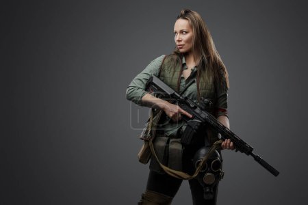 Foto de Tiro de estudio de mujer asesina profesional con rifle en el ajuste del apocalipsis posterior. - Imagen libre de derechos