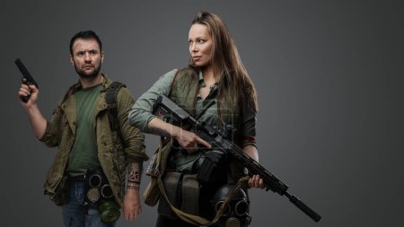 Foto de Estudio de sobrevivientes de pareja post apocalípticos con armas contra fondo gris. - Imagen libre de derechos