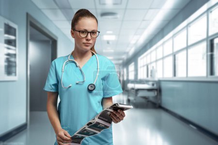 Foto de Inyección de enfermera vestida con bata azul con estetoscopio y rayos X en clínica moderna. - Imagen libre de derechos