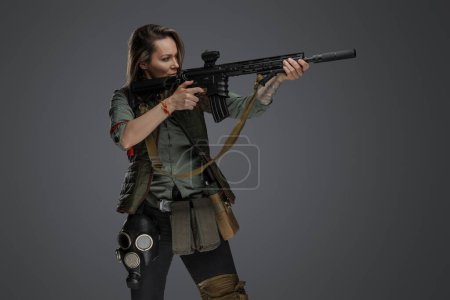 Téléchargez les photos : Portrait de femme militaire avec fusil regardant sur le côté isolé sur fond gris. - en image libre de droit