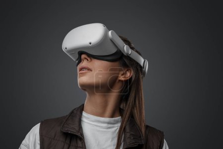 Foto de Aislado sobre fondo gris mujer con gafas innovadoras de realidad virtual. - Imagen libre de derechos