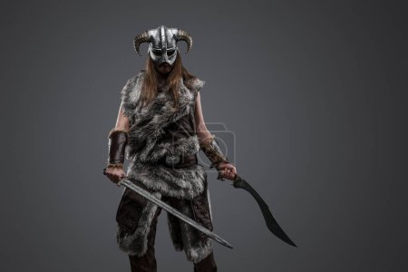 Foto de Retrato del antiguo guerrero escandinavo con espadas duales mirando fijamente a la cámara. - Imagen libre de derechos