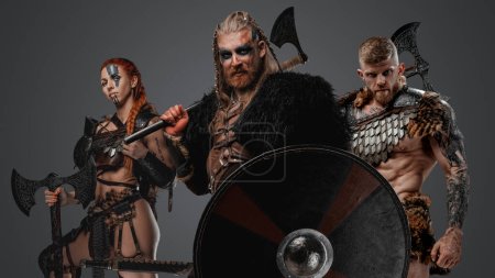 Foto de Estudio de vikingos antiguos con pieles y hachas sobre fondo gris. - Imagen libre de derechos