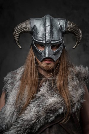 Foto de Retrato de vikingo del pasado con casco con cuernos mirando a la cámara sobre fondo gris. - Imagen libre de derechos