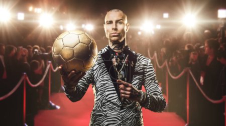 Foto de Retrato de hombre jugador de fútbol elegante vestido con atuendo de moda contra la alfombra roja y multitud. - Imagen libre de derechos