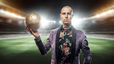 Téléchargez les photos : Art du joueur de football confiant vêtu d'une tenue élégante tenant le ballon de football. - en image libre de droit