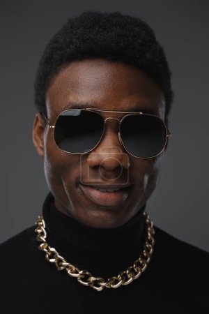 Photo for Studio shot of stylish black guy dressed in sweater and sunglasses with golden chain. - Royalty Free Image