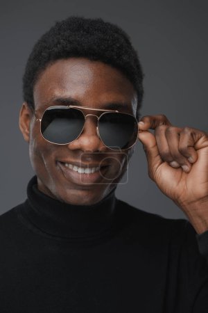 Photo for Shot of isolatedon grey background african man holding his sunglasses. - Royalty Free Image