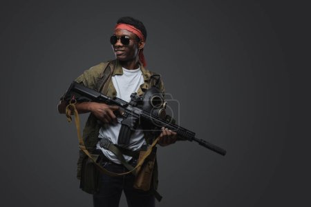 Photo for Shot of cheerful pirate of african ethnic with rifle in setting of post apocalypse. - Royalty Free Image