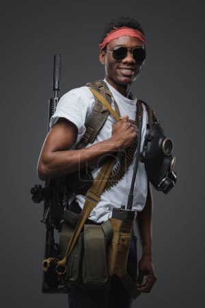 Photo for Shot of smiling buccaneer with military equipment and rifle in setting of post apocalyse. - Royalty Free Image