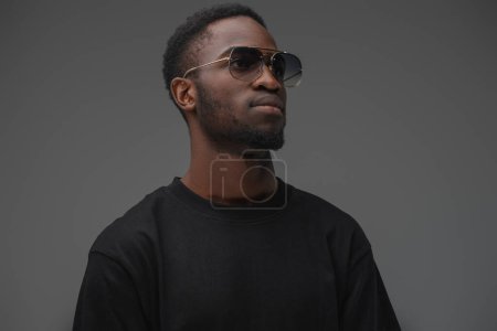 Photo for Shot of trendy black guy dressed in t shirt and sunglasses looking to side. - Royalty Free Image