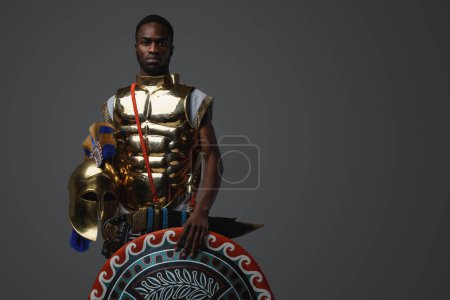 Photo for Shot of ancient greek soldier of african ethnic with shield and golden armor. - Royalty Free Image