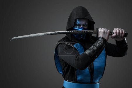 Téléchargez les photos : Portrait d'assassin de glace vêtu d'un costume avec capuche posant avec katana. - en image libre de droit