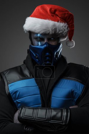 Photo for Studio shot of confident frozen assassin dressed in costume and christmas hat. - Royalty Free Image