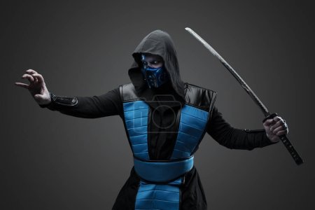 Prise de vue de ninja isolé sur fond gris avec le bras tendu.
