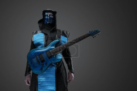 Foto de Shot of Ice ninja con cicatriz y guitarra eléctrica vestida con máscara y capucha. - Imagen libre de derechos