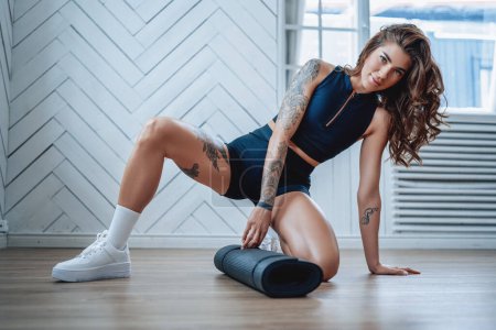 Photo for Domestic sport and leisire. Portrait of a seductive and stylish sportswoman preparing to workout on floor in modern room. - Royalty Free Image