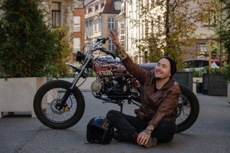 Téléchargez les photos : Portrait de motocycliste heureux avec vélo à l'extérieur à l'ancienne en journée. - en image libre de droit