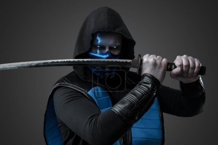 Téléchargez les photos : Portrait d'assassin de glace vêtu d'un costume avec capuche posant avec katana. - en image libre de droit