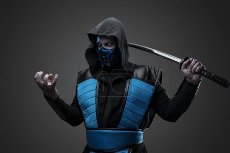 Téléchargez les photos : Prise de vue de ninja isolé sur fond gris avec le bras tendu. - en image libre de droit