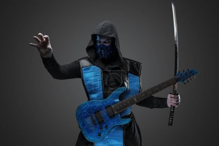 Téléchargez les photos : Prise de vue du guitariste Ice assassin avec katana vêtu d'un costume avec capuche. - en image libre de droit