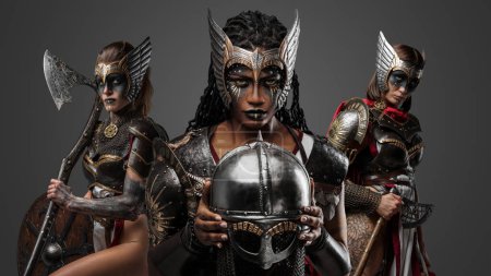 Téléchargez les photos : Prise de vue de trois guerriers femmes vêtues d'armures en acier avec lance et hache. - en image libre de droit