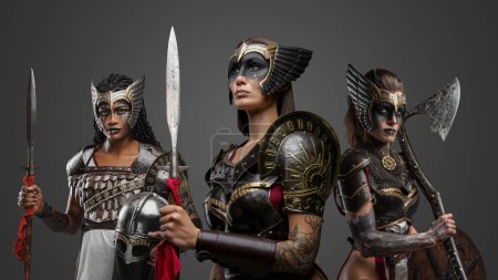 Foto de Retrato de tres atractivas guerreras vestidas con armaduras de hierro. - Imagen libre de derechos