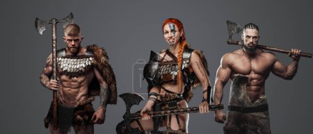 Téléchargez les photos : Plan studio de guerrière aux cheveux rouges et deux vikings sur fond gris. - en image libre de droit