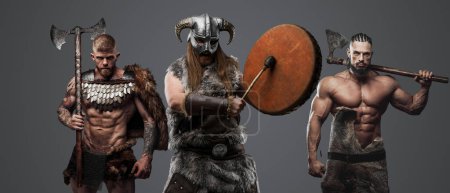 Foto de Tiro de vikingos antiguos con enormes hachas y tambor contra fondo gris. - Imagen libre de derechos
