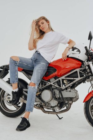 Foto de Estudio de tiro de aislado en fondo blanco mujer rubia y motocicleta moderna personalizada. - Imagen libre de derechos