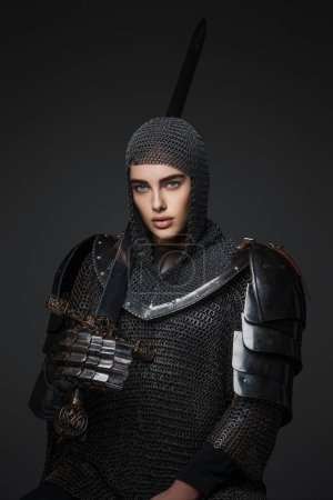 Téléchargez les photos : Superbe portrait d'une chevalier en armure médiévale pose avec confiance avec son épée tirée, exsudant force et détermination - en image libre de droit
