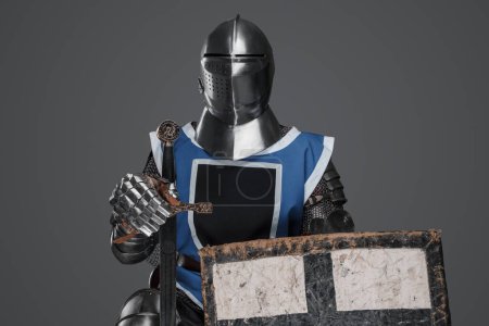 Téléchargez les photos : Chevalier médiéval coiffé d'un manteau bleu avec épée et bouclier sur fond gris - en image libre de droit