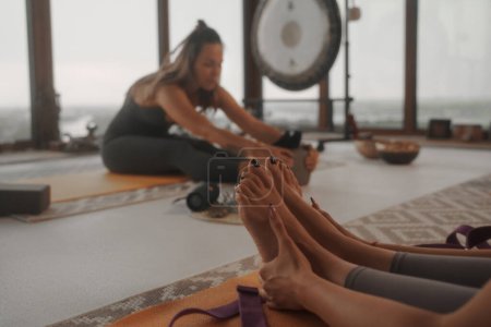 Téléchargez les photos : Une séance de yoga paisible dans un appartement luxueux surplombant le paysage urbain, en se concentrant sur la vue rapprochée des pieds des participants - en image libre de droit