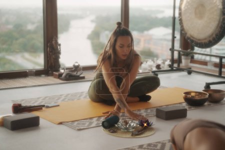 Photo for A woman in sportswear practicing yoga in a peaceful setting within an apartment, with a panoramic cityscape in the background - Royalty Free Image