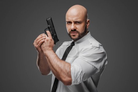 Téléchargez les photos : Un individu barbu en tenue blanche craquante prépare son arme à feu, suggérant des rôles de sécurité ou de détective - en image libre de droit