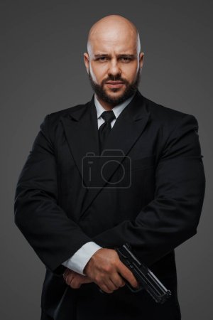 Photo for Determined bodyguard in formal attire poised with pistol, capturing his commanding presence - Royalty Free Image