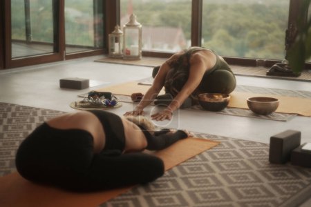 Photo for Group of girls practicing yoga and meditation in a city apartment with panoramic views - Royalty Free Image