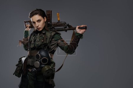 Foto de Retrato de una soldado con atuendo militar, sosteniendo un rifle automático hecho en casa, que representa a un rebelde o partisano en un conflicto de Oriente Medio sobre un fondo gris - Imagen libre de derechos