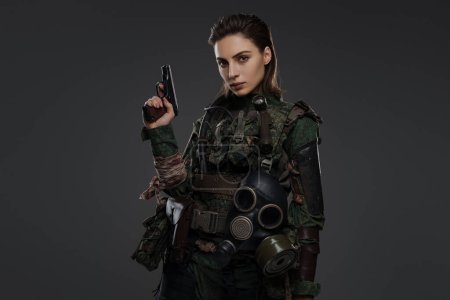 Photo for Female warrior dressed as a rebel or partisan in military garb, armed with a pistol, set against a neutral background, representing turmoil in the Middle East - Royalty Free Image