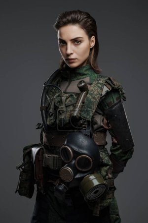 Foto de Mujer soldado confiada en atuendo militar posando sobre un fondo gris, representando el conflicto de Oriente Medio - Imagen libre de derechos