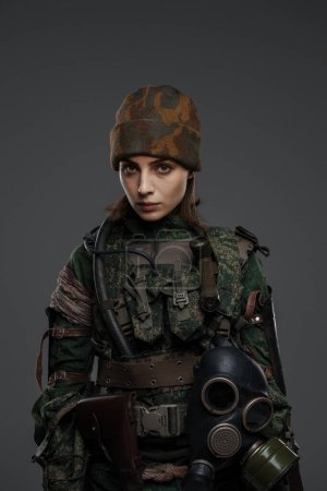 Téléchargez les photos : Femme courageuse soldat avec la main blessée en uniforme militaire, symbolisant la résistance dans un conflit au Moyen-Orient, sur un fond gris - en image libre de droit