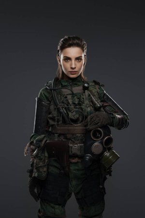 Photo for Portrait of a woman in military attire, portraying a rebel or partisan, against a gray background, depicting a Middle Eastern conflict - Royalty Free Image