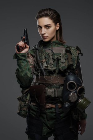 Foto de Guerrera vestida de rebelde o partidista con atuendo militar, armada con una pistola, colocada sobre un fondo neutral, representando agitación en el Medio Oriente - Imagen libre de derechos